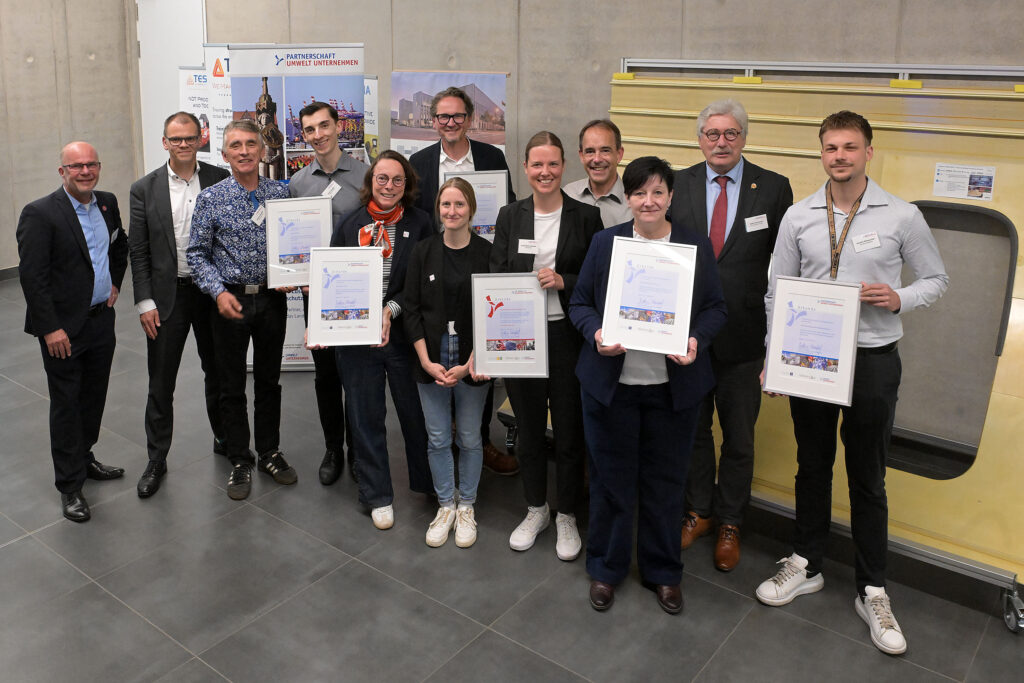 Gruppenfoto der neuen Mitglieder der Partnerschaft Umwelt Unternehmen und des ausgezeichneten Klimaschutzbetriebs gemeinsam mit Staatsrat Jan Fries und Martin Schulze von der Geschäftsstelle Umwelt Unternehmen.